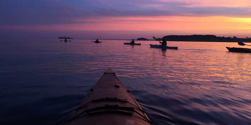 Kayaks paddle during a sunrise