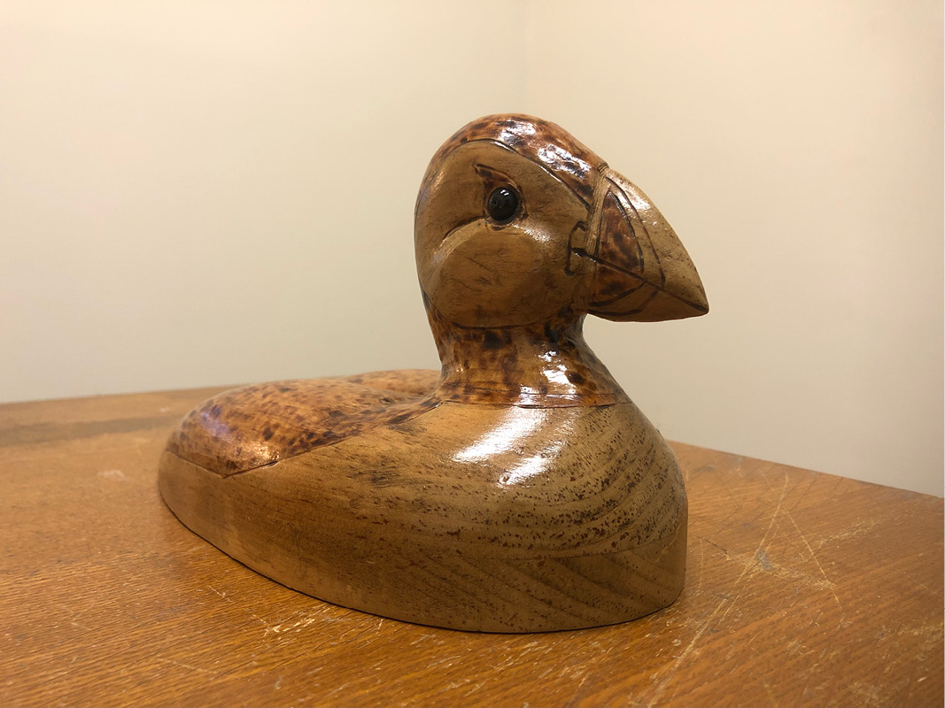 A carved wooden puffin with a shiny coating