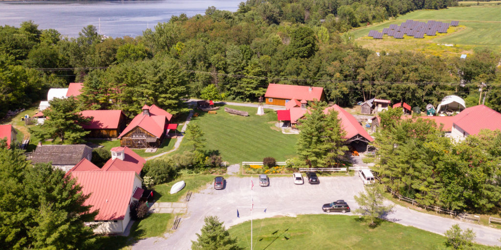 Aerial view of Lake Champlain Maritime Museum with several red roofs and a green grassy lawn