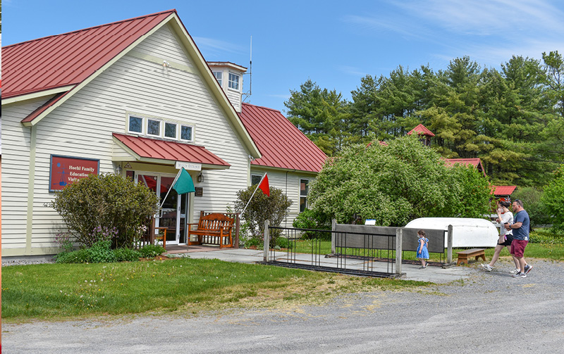 Little girl with two adults walking into white building with red roof