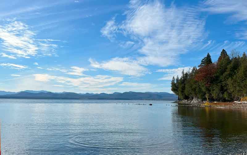 A view of Lake Champlain with blue skies and mountains in the distance.