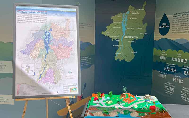 A map of the Lake Champlain Watershed next to a plastic model of a moutain range